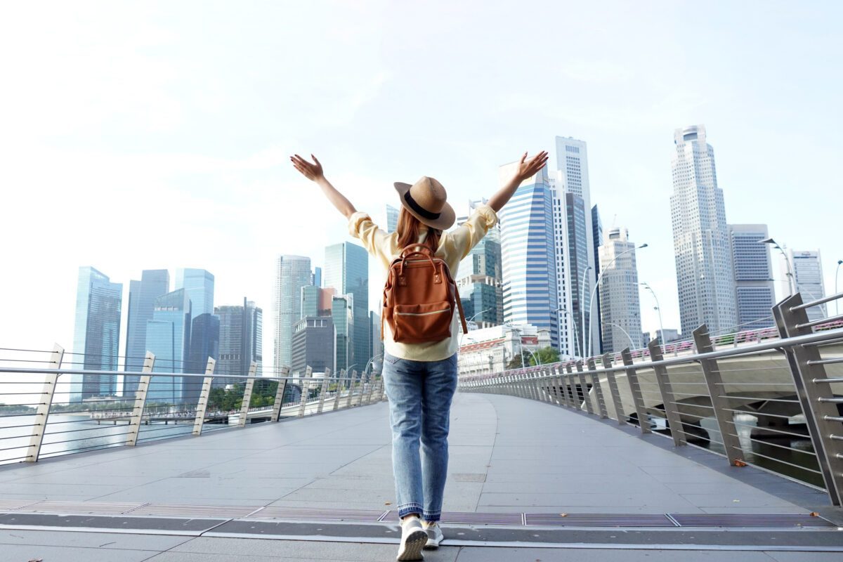Young woman traveler with backpack and hat traveling into Singapore city downtown.