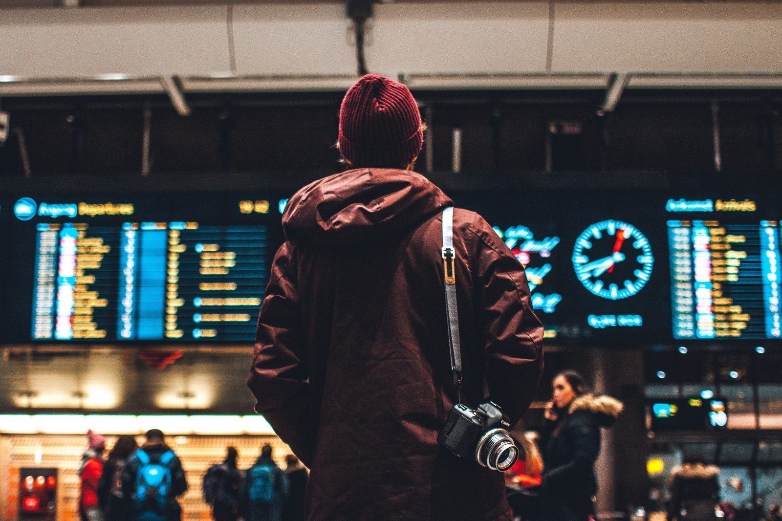 person looking up at flight schedules in an airport