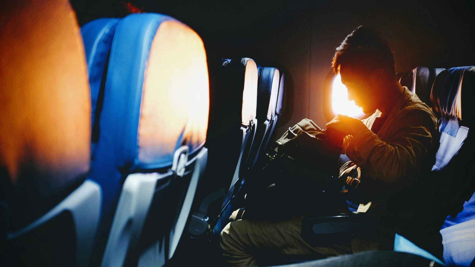 man looking out of his plane window at sunrise or sunset