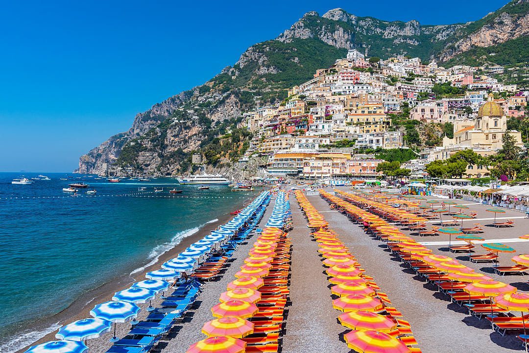 Beach filled with umbrellas during the high season in Positano, Italy