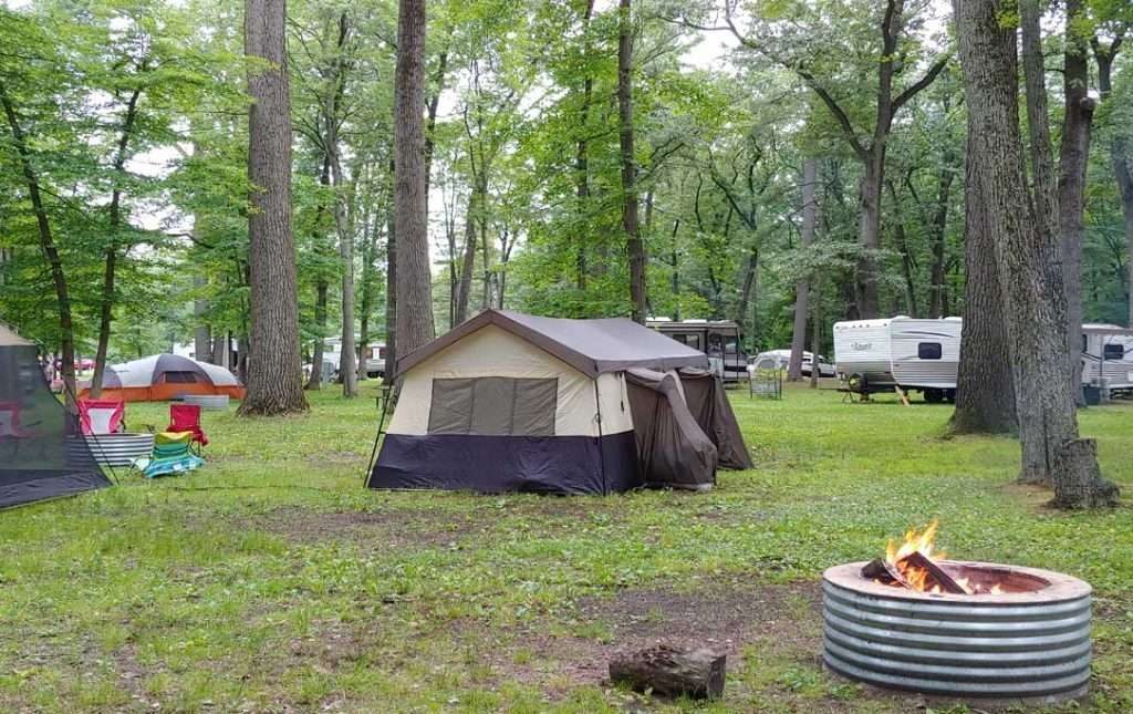 Campsite at Bay City State Park featuring a large beige and brown tent surrounded by trees and RVs, illustrating a slower, more flexible travel style.