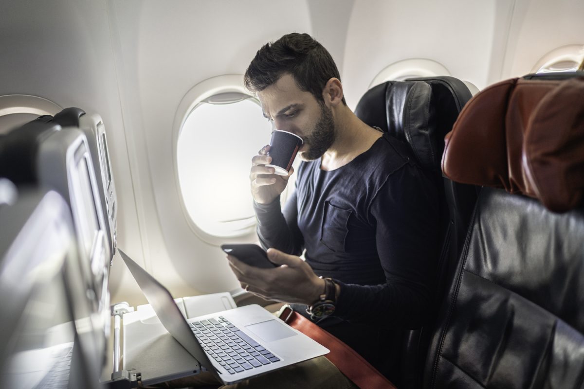A person on a plane on their laptop and phone