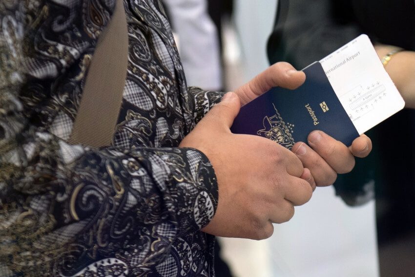 Traveler holding a passport with a plane ticket inside, ready to board.