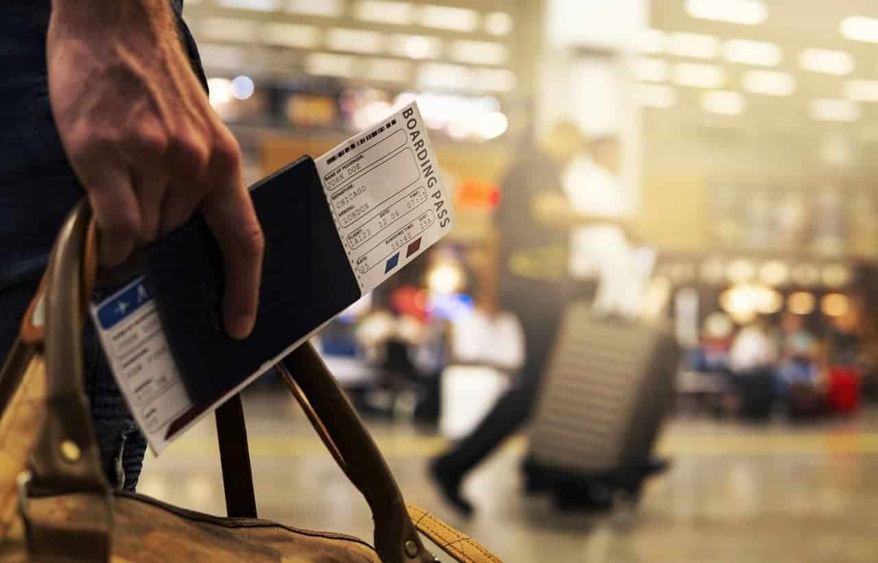 A man holding his boarding pass, passport and carry-on bag at the airport