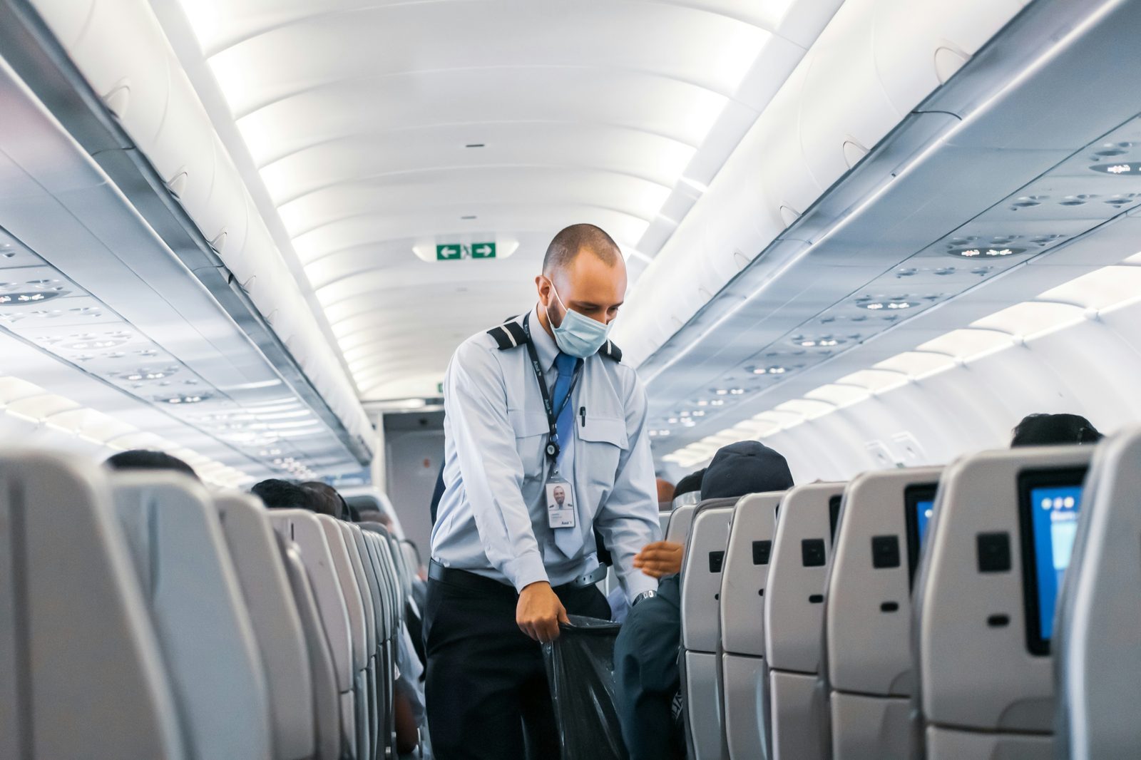 man standing in airplane aisle stretching during flight