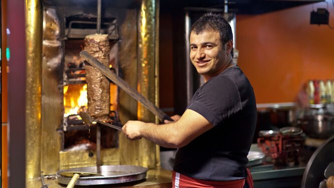 Gyro vendor carving meat at a street food stand
