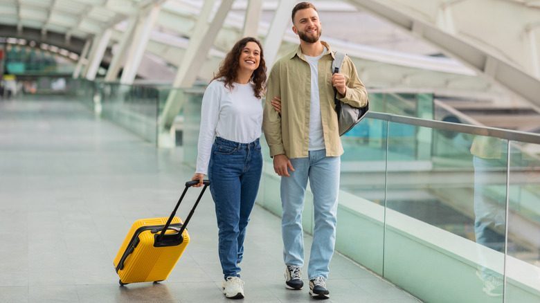 Smiling couple walking around an empty airport terminal