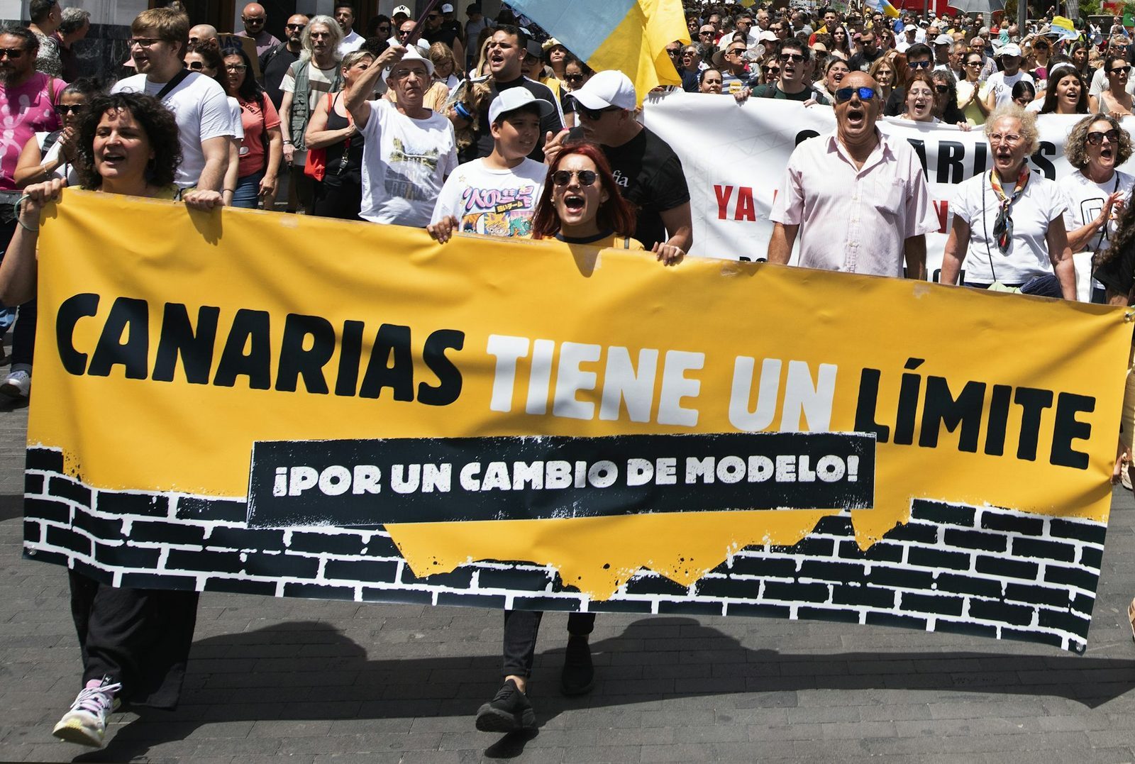 People at a demonstration carry a large banner reading: 'Canary Islands have limits, for a change of model.'