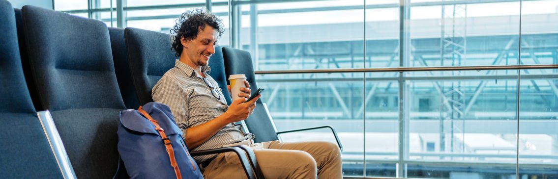 Traveler checking their phone for rebooking options during a flight disruption.