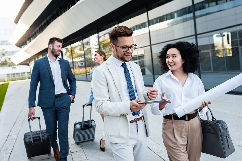 Group of coworkers on a business trip discussing logistics outside an office building