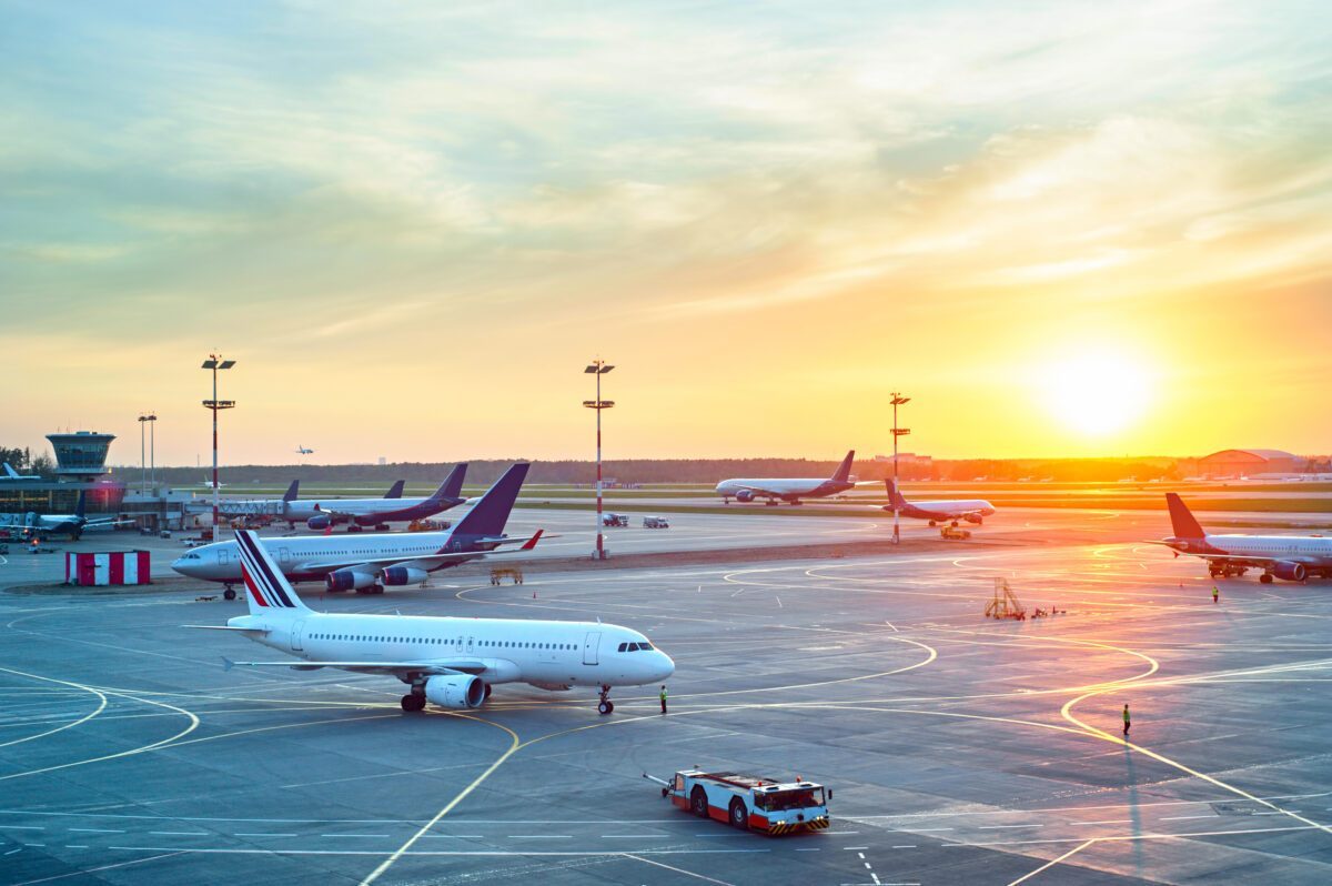 Planes sit on the runway at the airport with a view of the sunset