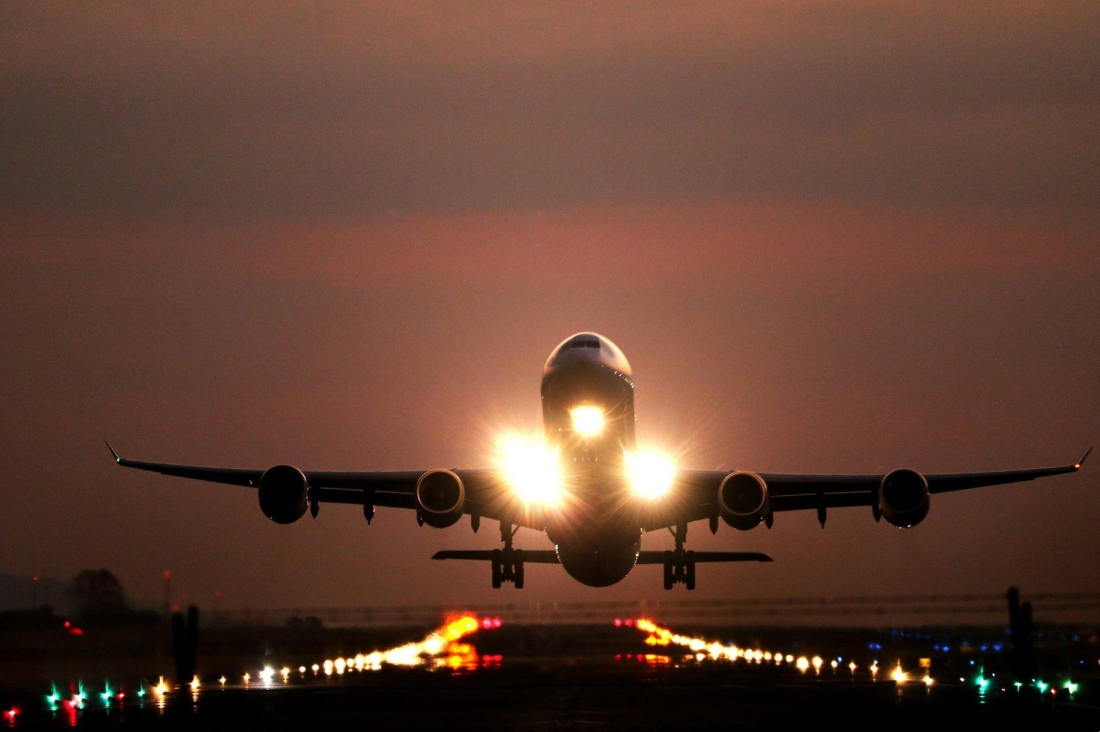 Airplane taking off at night with runway lights
