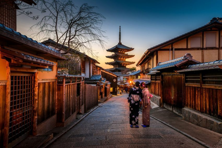 Two women in colorful kimonos walking down a street in Japan, suggesting cultural travel experiences.