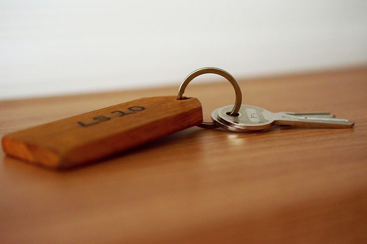 Wooden hotel key tag with keys on a wooden surface, suggesting traditional hotel security and reliability.