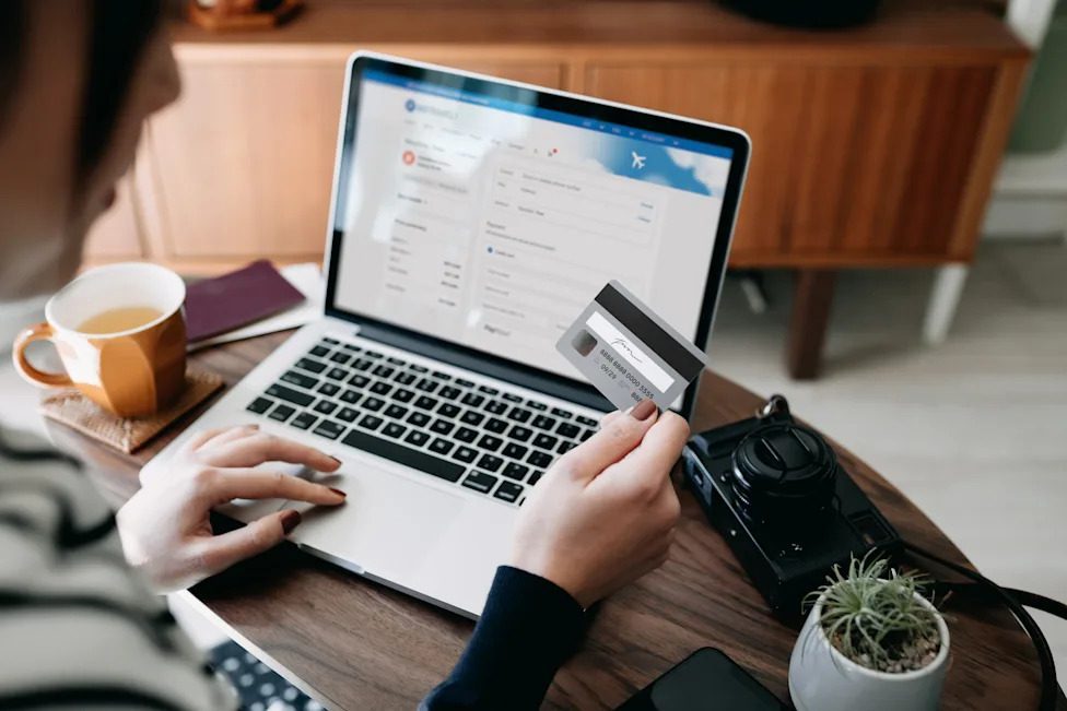 Traveler booking flights online with a laptop and credit card.