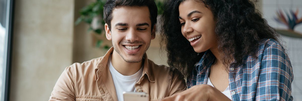 Couple smiling while reviewing something on smartphone screen