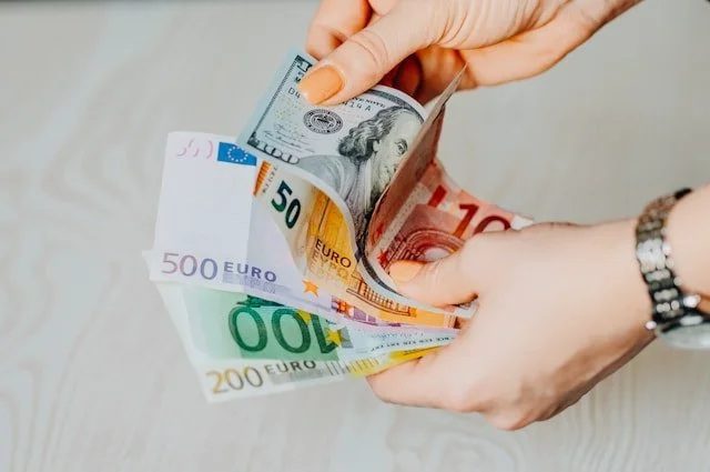 Hands counting euros and dollars.