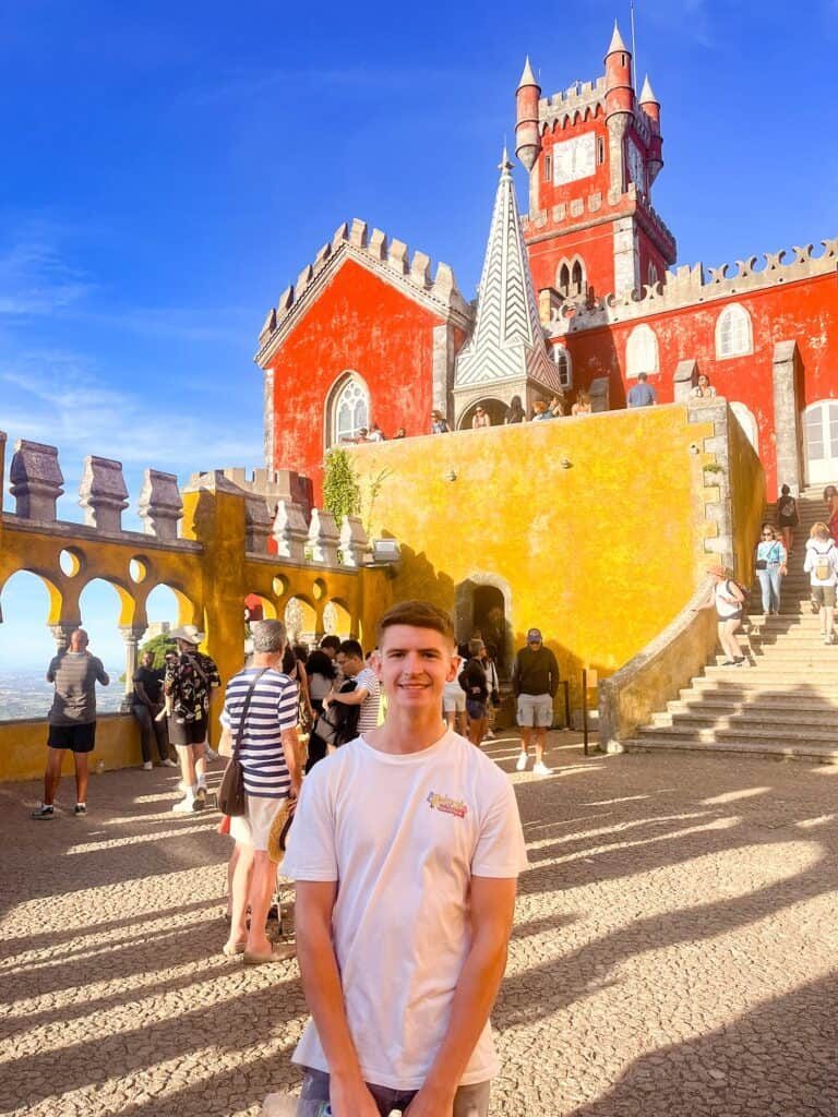 Traveler standing before Pena Palace in Sintra, Portugal, showing that some European destinations can still be budget-friendly.