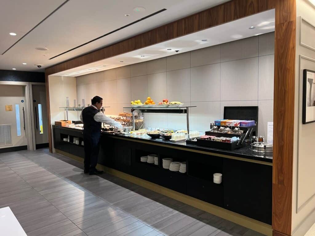 Buffet and seating area inside an airport lounge, offering food and a comfortable place to wait before a flight