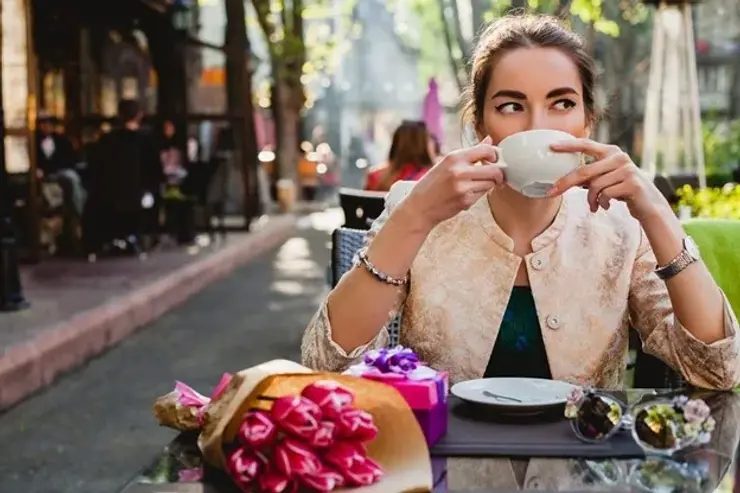 Woman sipping coffee at an outdoor café, relaxed street scene