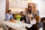 Friends sharing a meal around a table in a home-style kitchen