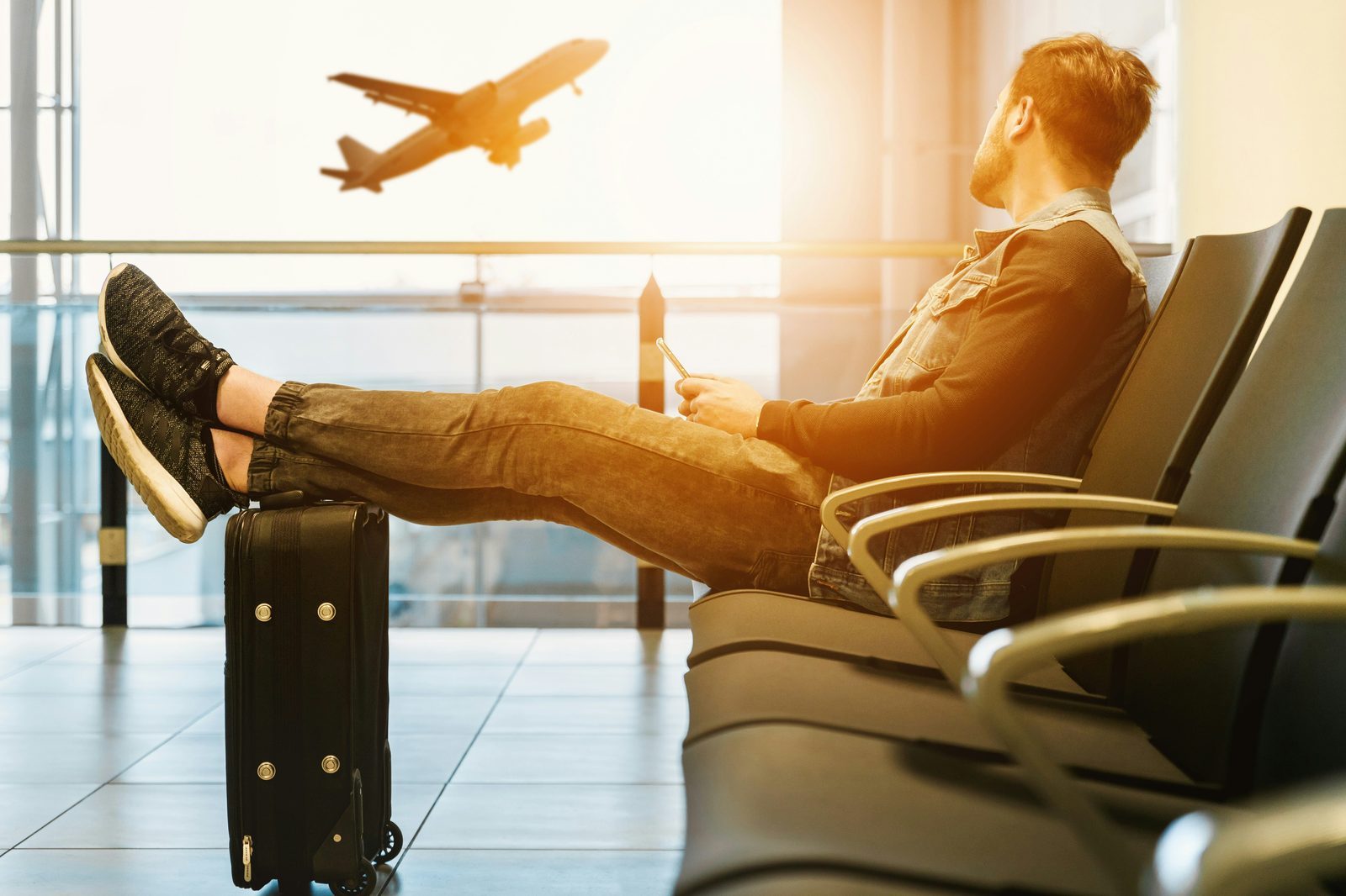 Traveler sitting in an airport terminal looking at an airplane
