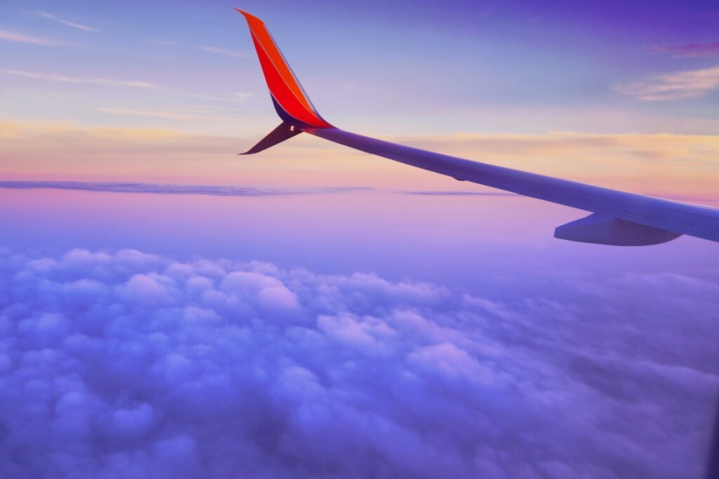 Airplane wing over sunset clouds, symbolizing evening and night flights
