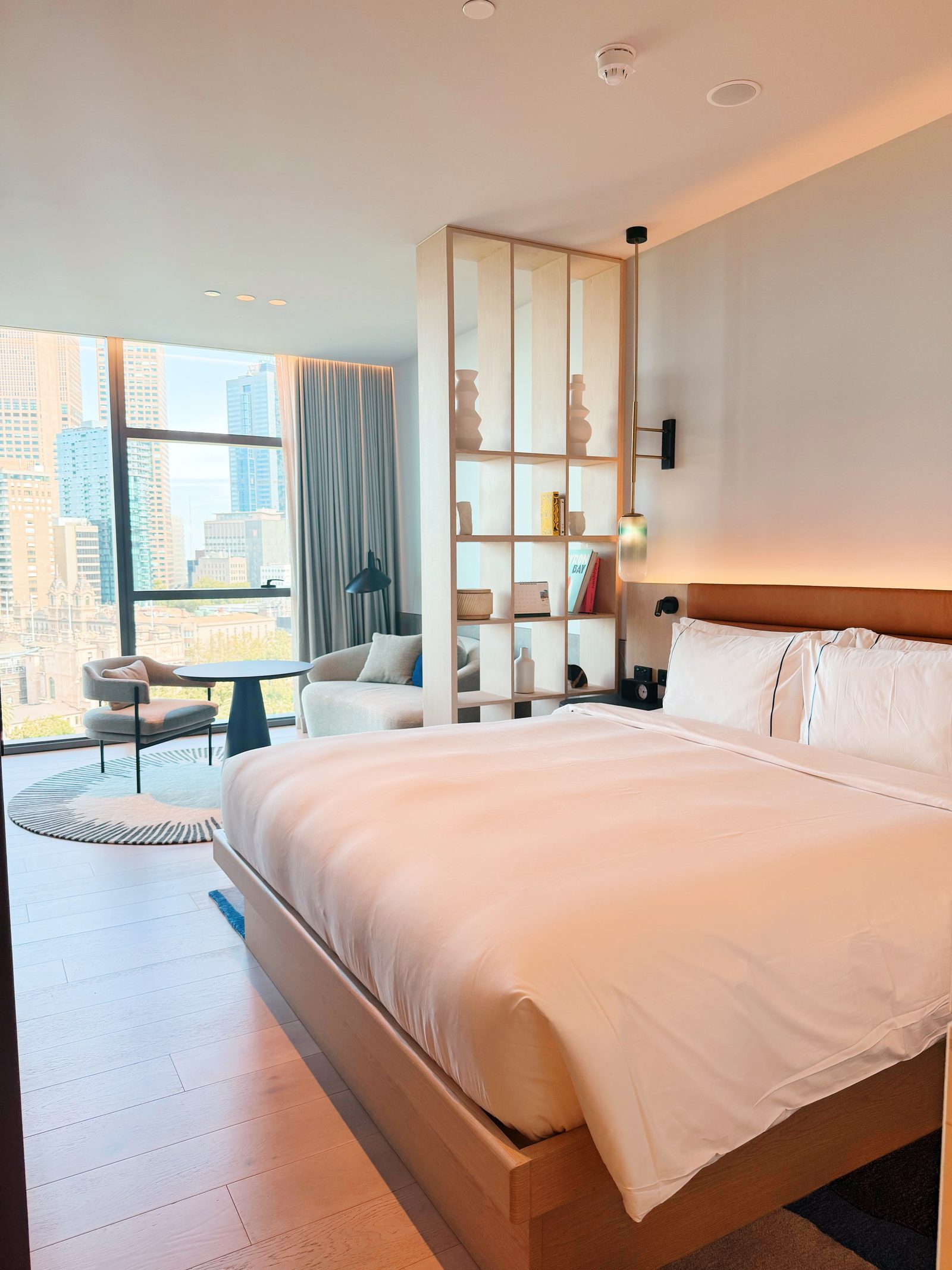 Modern hotel room with a large bed and city view, representing flexible, refundable accommodation options.