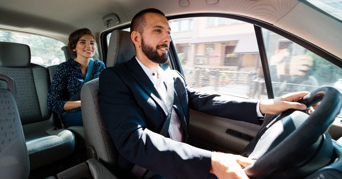 Taxi driver sitting in a car with businesswoman