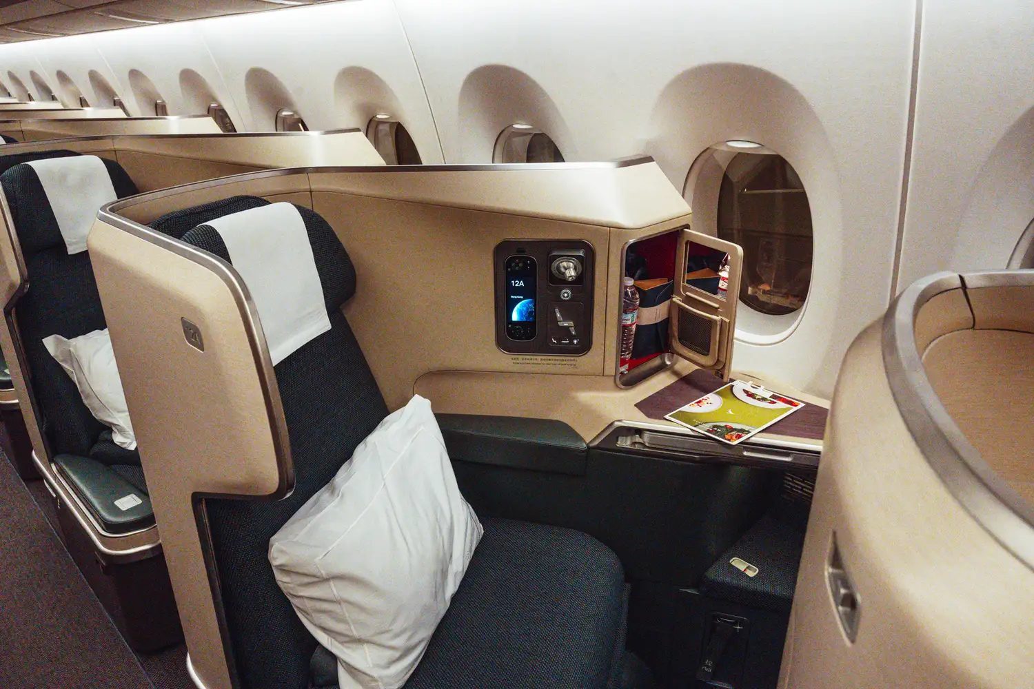 First-class airline seat equipped with a pillow and refreshments, illustrating a more comfortable long-haul experience