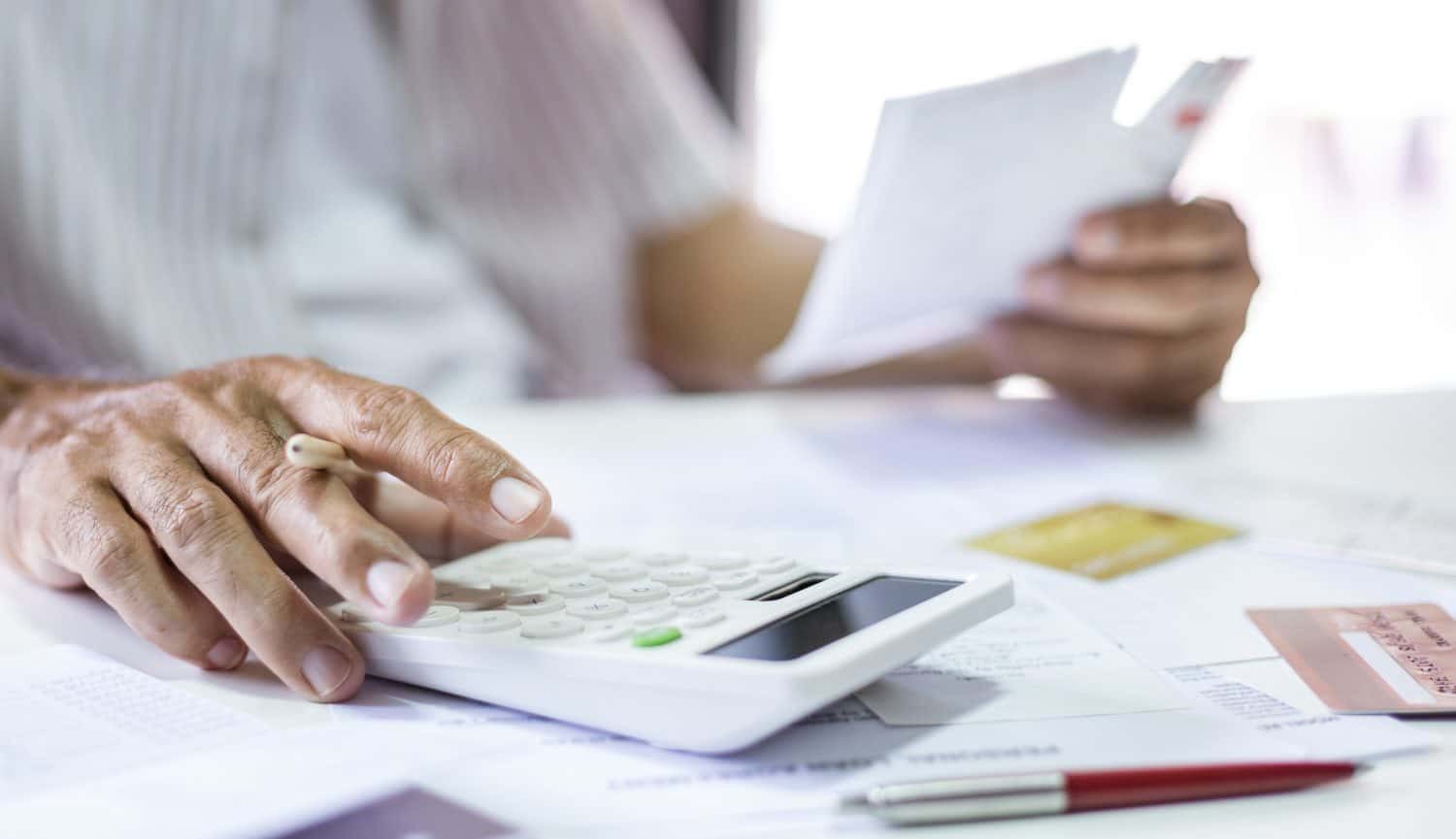Person calculating expenses and credit card bills at a table