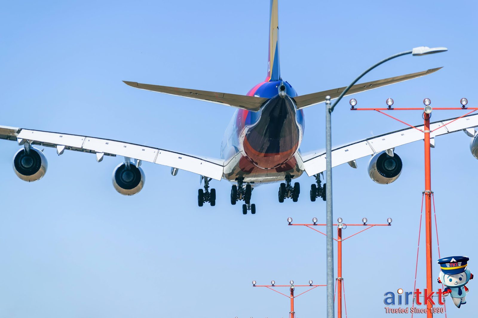 Airplane landing at a small airport runway under a clear daytime sky