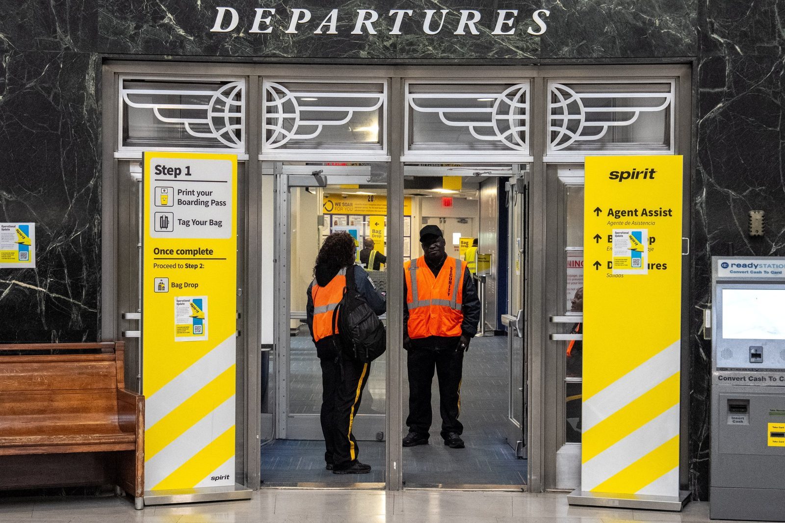 Security guards stand at the door of a boarding gate where signs inform passengers of the shutdown of Spirit Airlines at LaGuardia Airport in Queens, in New York City